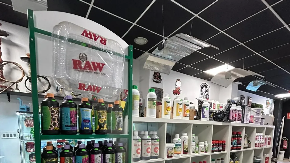 Estanterías con botellas de fertilizantes y aditivos ordenadas por marca, y reflectores de iluminación colgados del techo